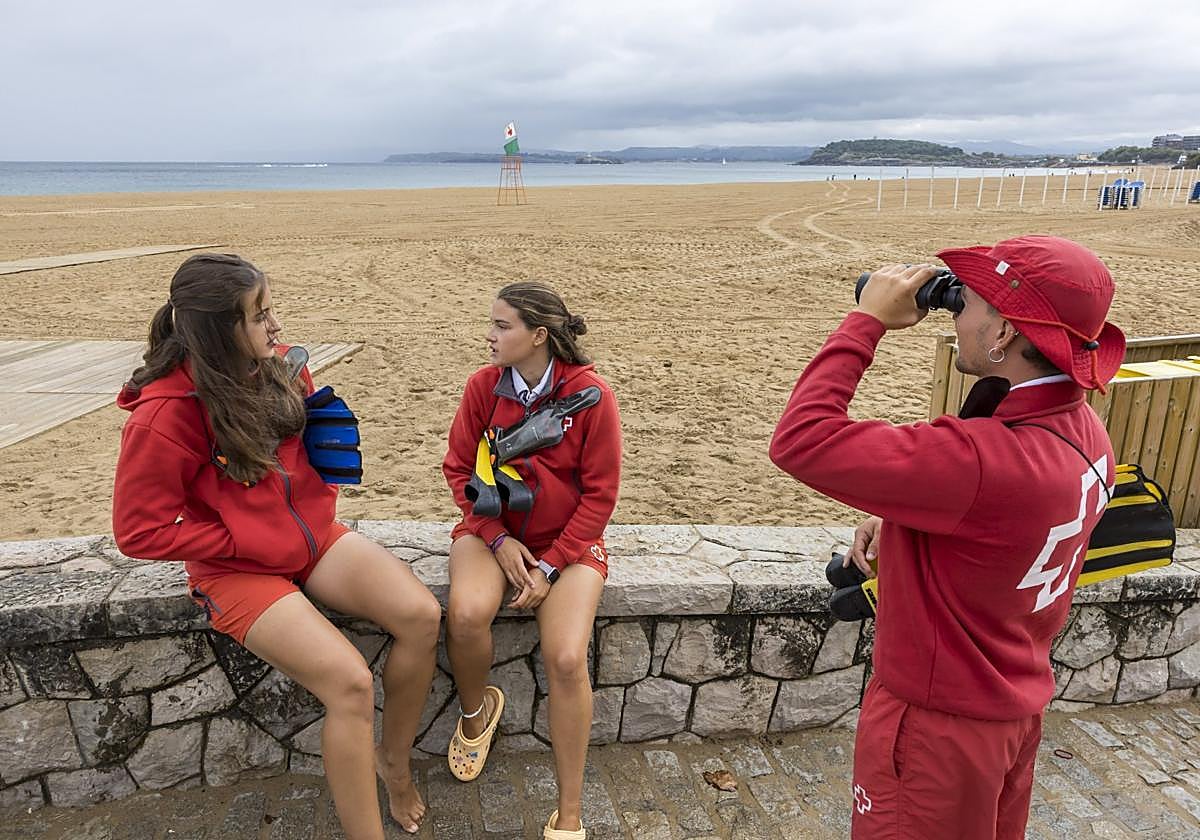 Javier Martos mira por los prismáticos frente a la Segunda Playa de El Sardinero junto a dos compañeras.