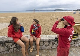 Javier Martos mira por los prismáticos frente a la Segunda Playa de El Sardinero junto a dos compañeras.