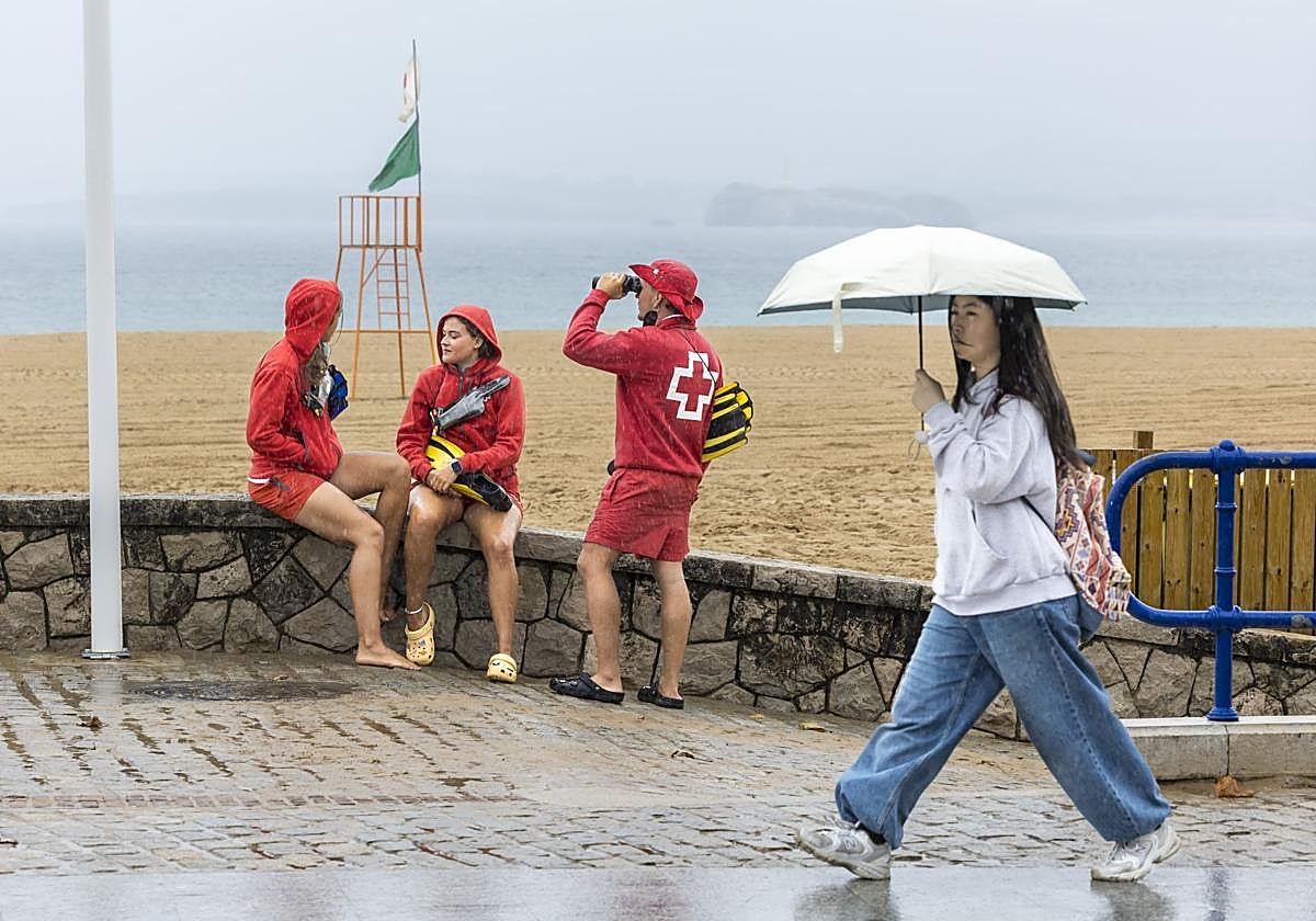 Los socorristas de La Cruz Roja mantienen su vigilancia una Segunda playa del Sardinero, vacía por culpa de la lluvia.