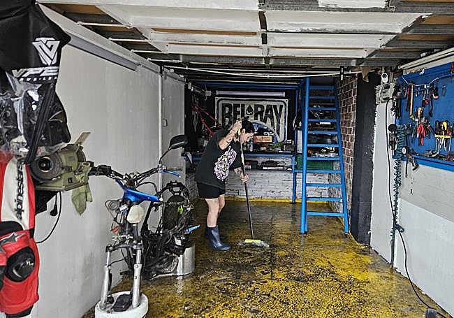 Lucía Gutiérrez, dueña de un pequeño taller del barrio, sacando el agua con una escoba.