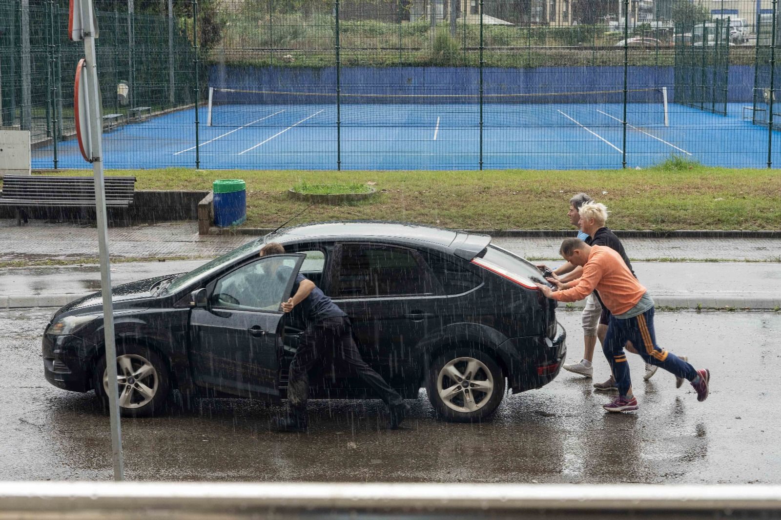 Vecinos de Maliaño empujando un coche afectado por las inundaciones