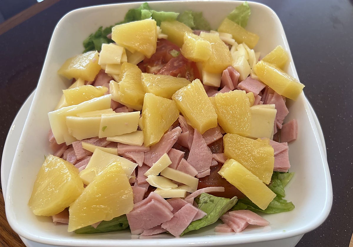 Ensalada tropical con lechuga, tomate, jamón york, queso y piña.