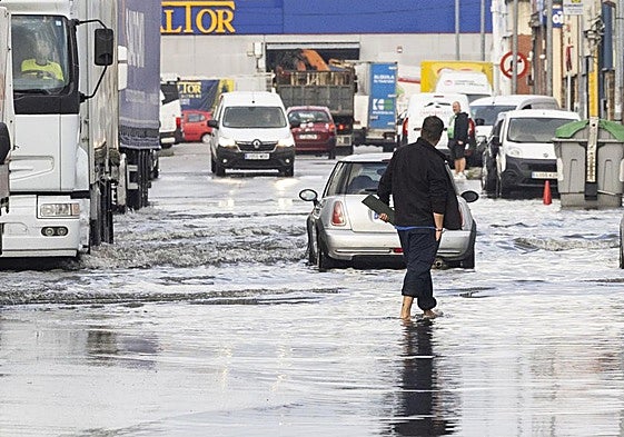 Un hombre camina con el agua a la altura de los tobillos en el polígono de Candina de Santander.