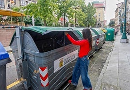Una mujer deposita basura en un contenedor de la calle Francisco Díaz.