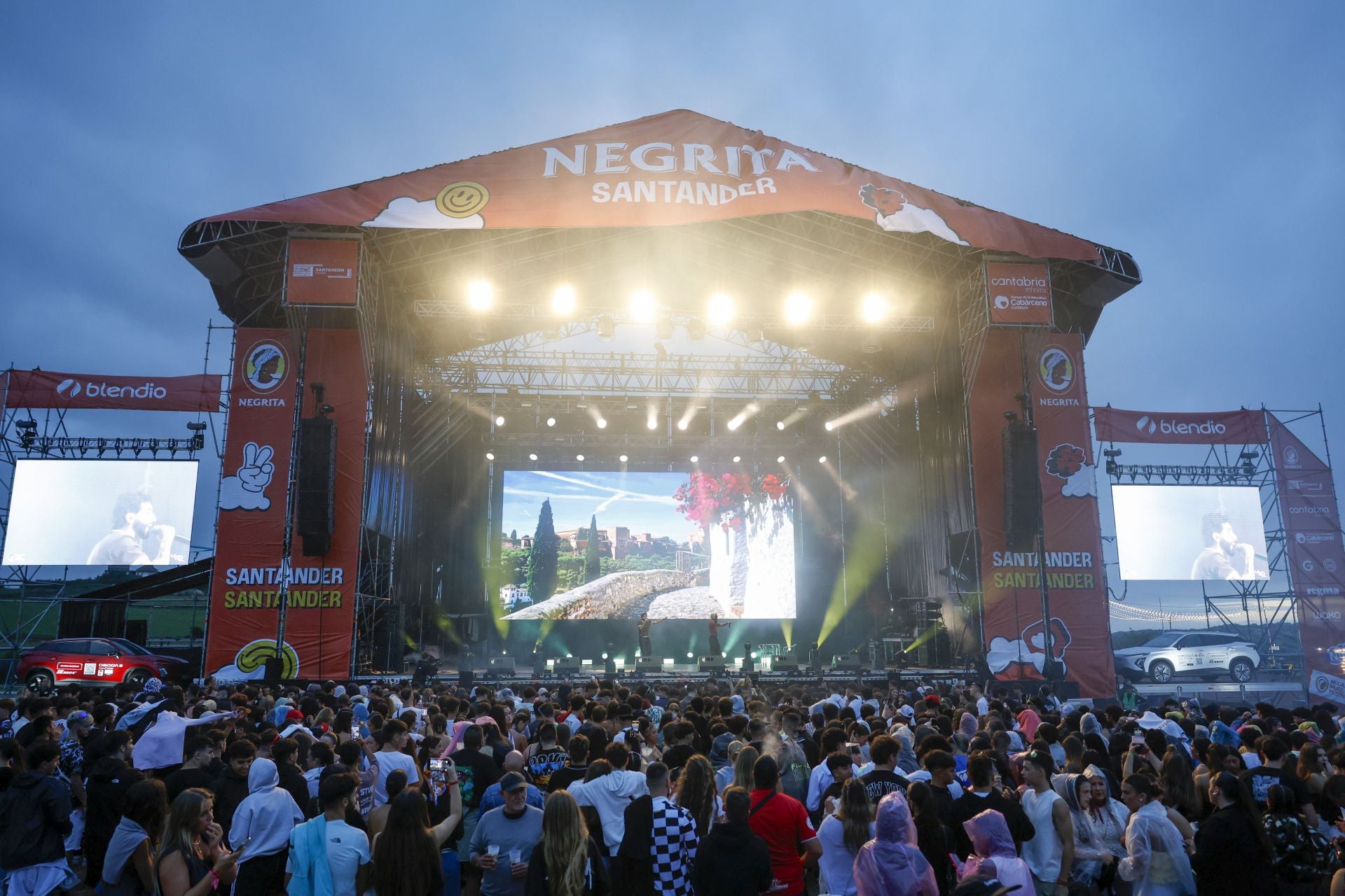 Entre la multitud, algunos asistentes con chaquetas impermeables se preparan ante el cielo que se oscurece y amenaza lluvia.