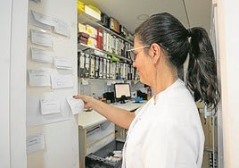 Empleada de una farmacia revisa una notas.