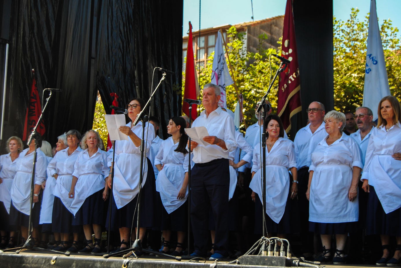 Todos los integrantes de la coral han subido al escenario luciendo vestimenta marinera. 