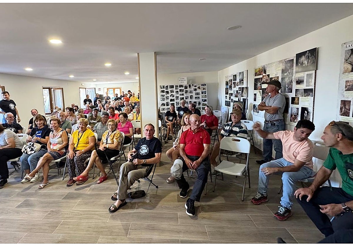 Imagen principal - El salón de usos múltiples lleno de público para escuchar la conferencia; comida de hermandad de vecinos de Tresviso con los espeleólogos de la Universidad de Lancaster, y Fernando Rivero, capitán del Greim de Jaca durante su intervención