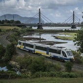 El tren camino de Santander, a punto de pasar bajo el viaducto de Treto, en las marismas de Santoña y Joyel.