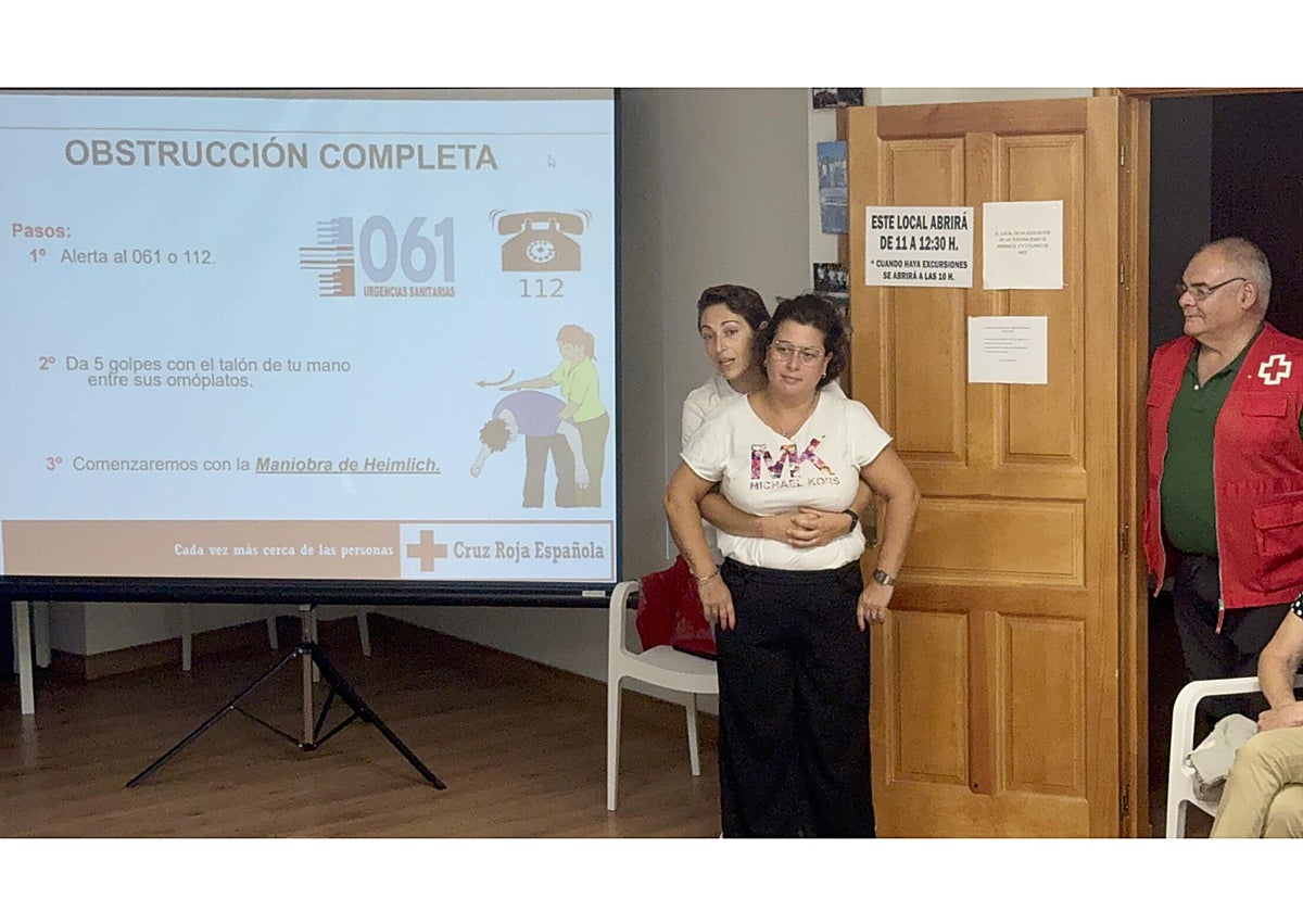 Imagen secundaria 1 - Asistentes al taller, realización de la maniobra de Heimlich con una voluntaria, y Tamara Alonso enseñando a colocar los parches del desfibrilador