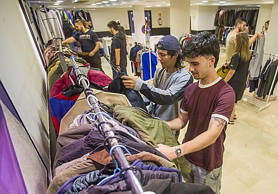 Varios jóvenes revisan la ropa a nueve euros en el sótano del NH.