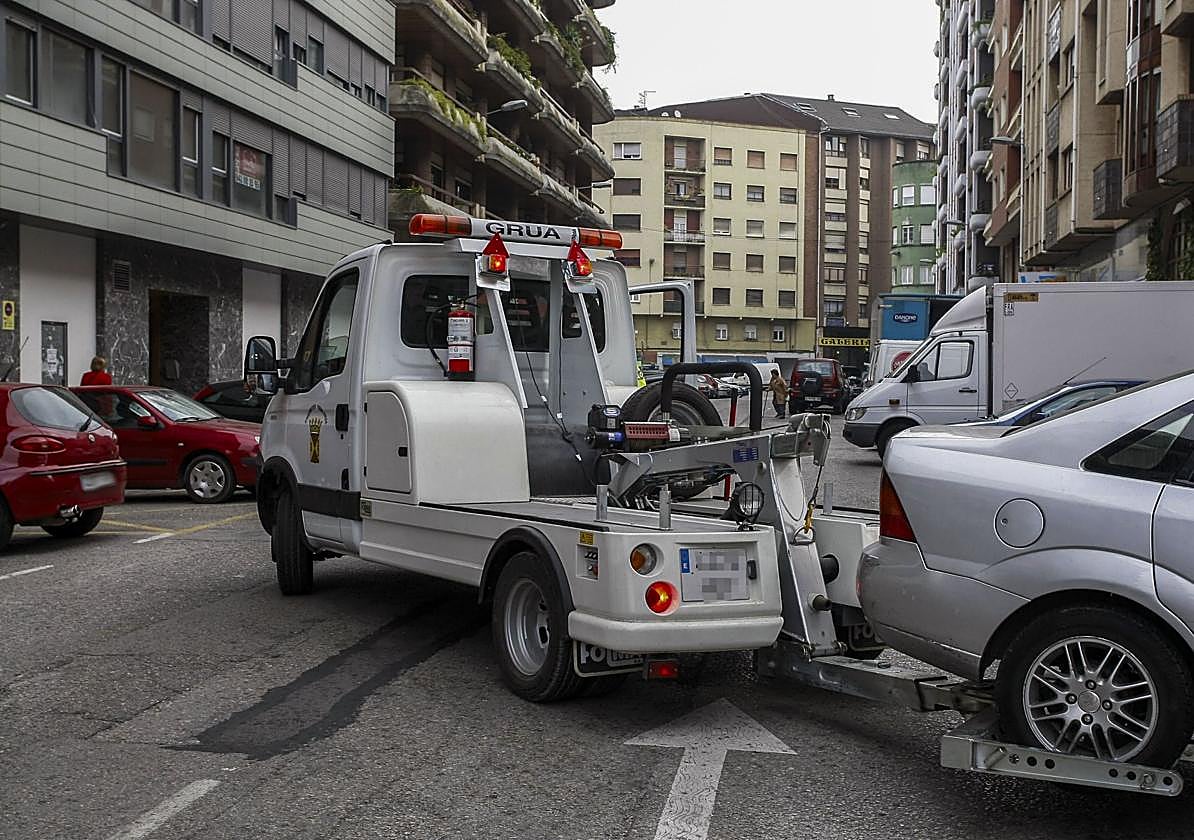 Una grua municipal retira un vehículo mal estacionado en Torrelavega.