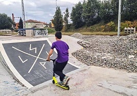 Un joven recorre las pistas de La Lechera con su patinete, el pasado domingo, junto a la obra del desvío del tren, en Torrelavega.