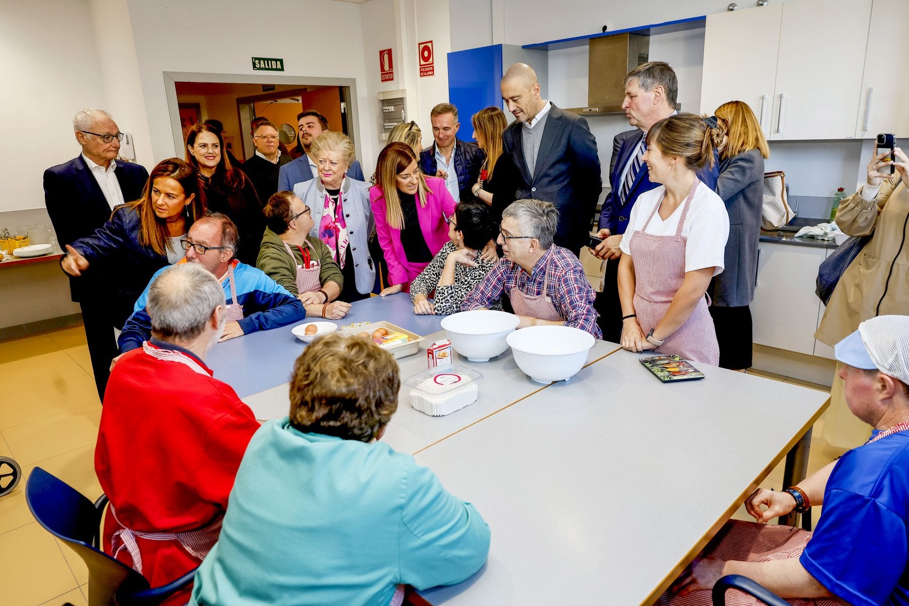 Buruaga charla con los usuarios del centro junto a la presidenta de la Fundación Asilo, el alcalde y la consejera de Inclusión Social.