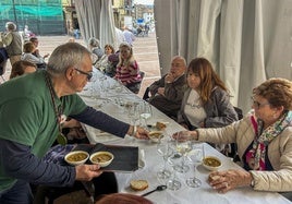 Uno de los miembros de la Cofradía de los Cocidos de Cantabria sirve a los asistentes.