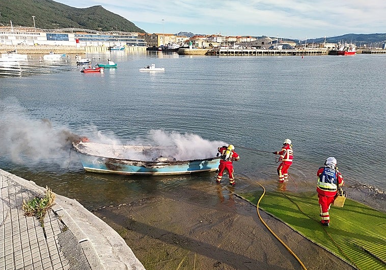 Los bomberos del 112 sofocan las llamas de la embarcación.