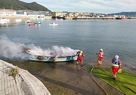 Los bomberos del 112 sofocan las llamas de la embarcación.
