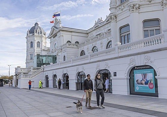 Una pareja pasea con su perro junto al Casino de El Sardinero, en la Plaza de Italia.