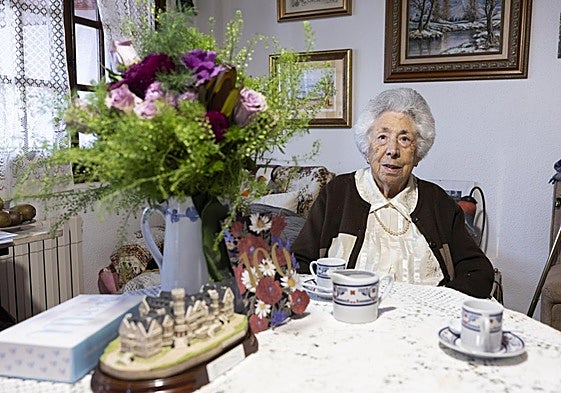 Martina Mújica en el salón de su casa, con su tarjeta de felicitación, un ramo de flores y la miniatura del Palacio de la Magdalena.