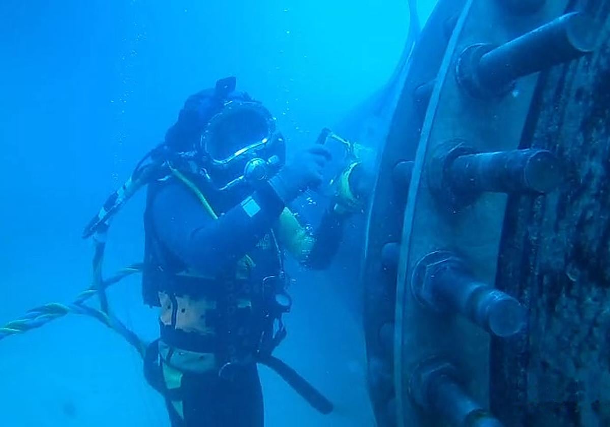 Un buzo profesional durante el proceso de instalación de una tubería subacuática.