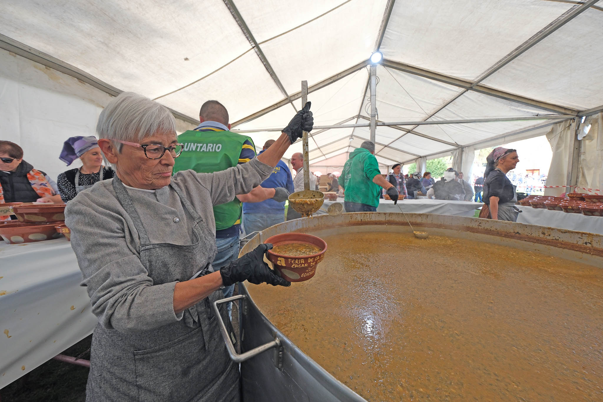 Una de las voluntarias sirve el gran cocido montañés. 