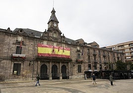 Vecinos caminan frente al Palacio municipal de Torrelavega.