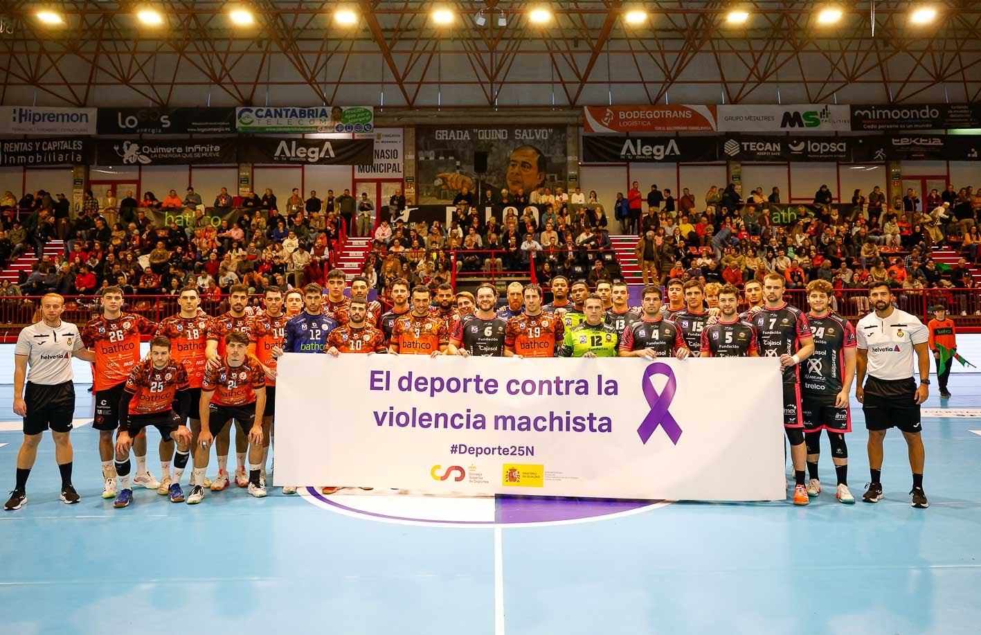 Los jugadores del Bathco y del Puente Genil sostiene una pancarta con el lema  "El deporte contra la violencia machista"