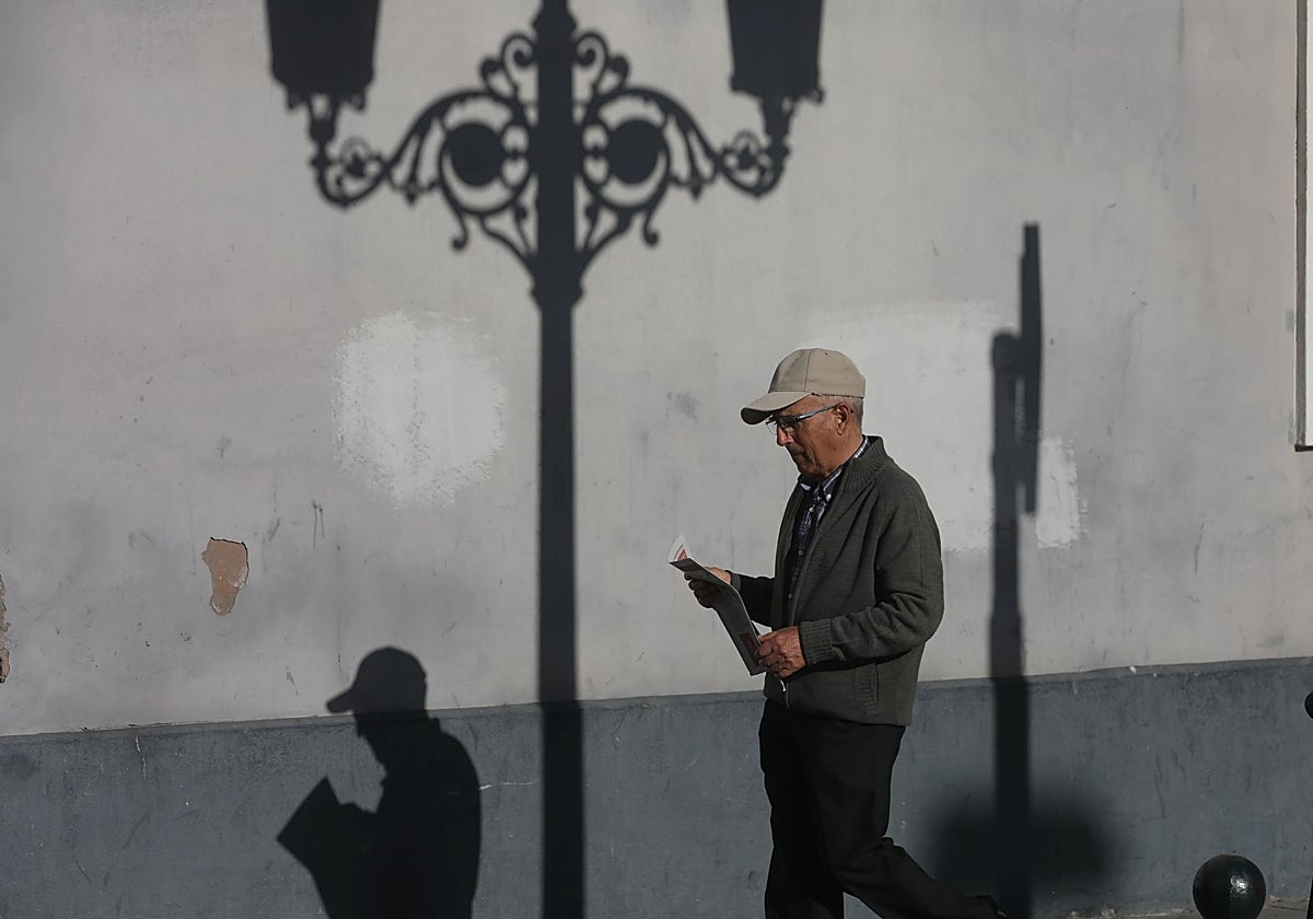 Un jubilado camina con un periódico por la calle.