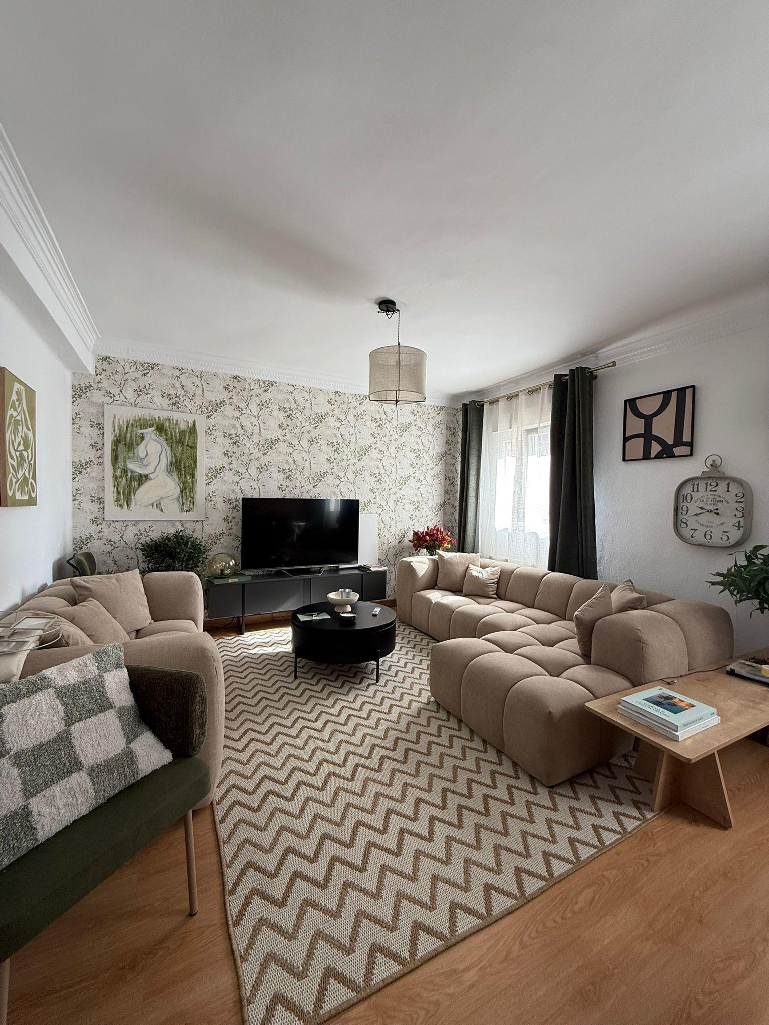 Dos sofás modulares en tonos neutros marcan la distribución de este piso de Santander, en el que una alfombra de espiga y la mesa de centro oscura redondean la escena.