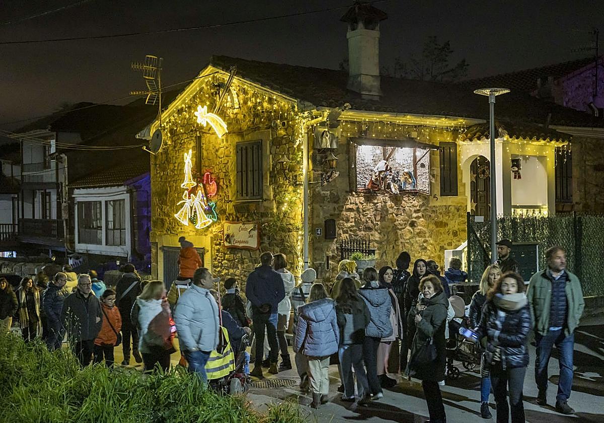 Visitantes transitan entre las casas iluminadas de Quijano en la Navidad de 2024.
