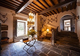 Hall de entrada en el que destaca la sólida escalera de piedra, la colección de cornamentas de la pared y una lámpara que refuerza el carácter noble del inmueble.