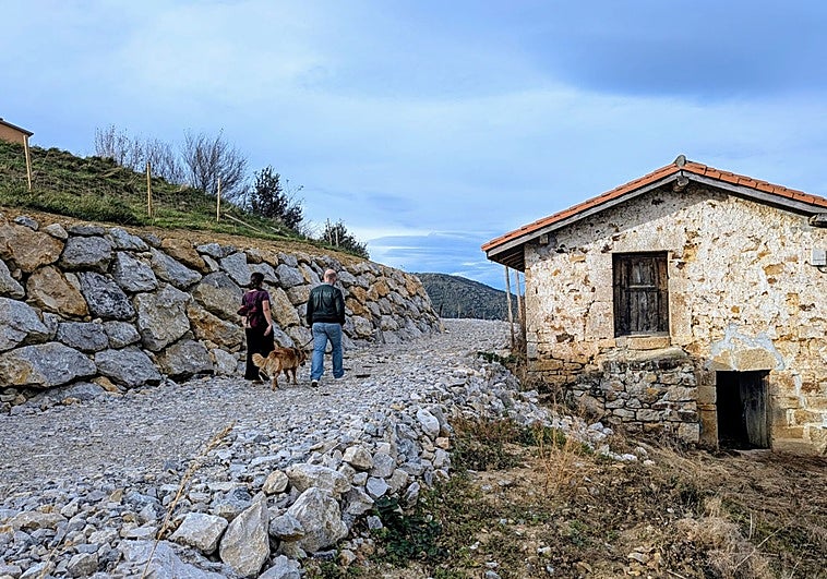 Una pareja pasea por el camino ahora paralizado junto a una cabaña semienterrada por el vial.