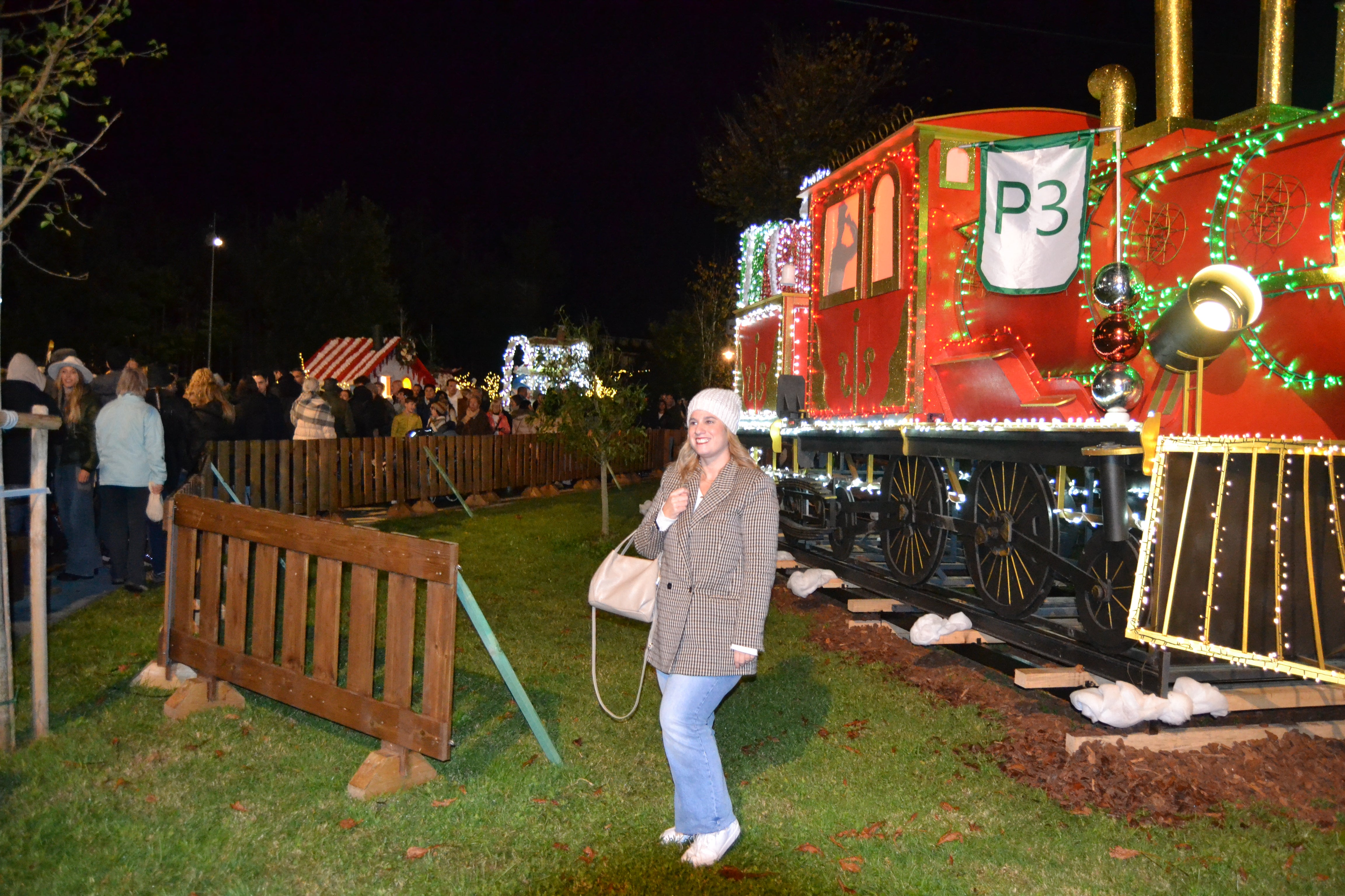 Una  chica se fotografía junto a un luminoso tren. 