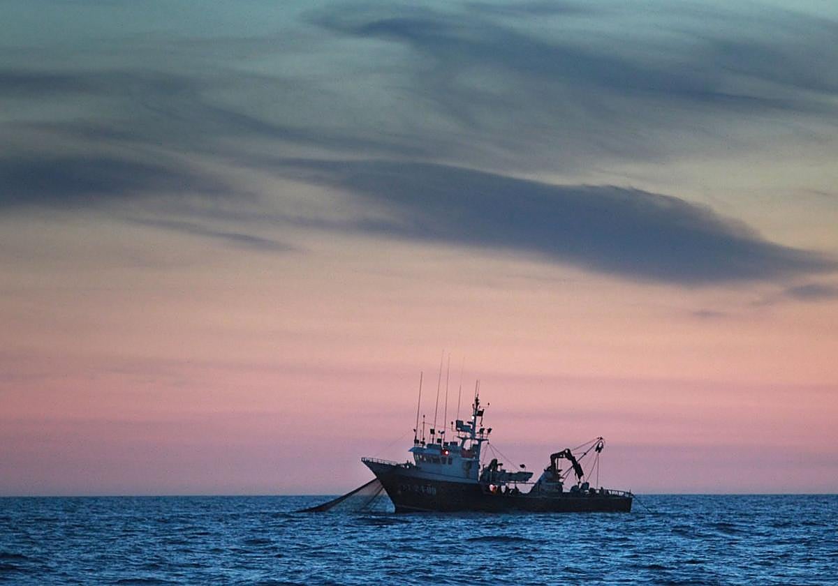 Un barco cántabro rastrea bocarte por el Cantábrico con el sol despuntando.