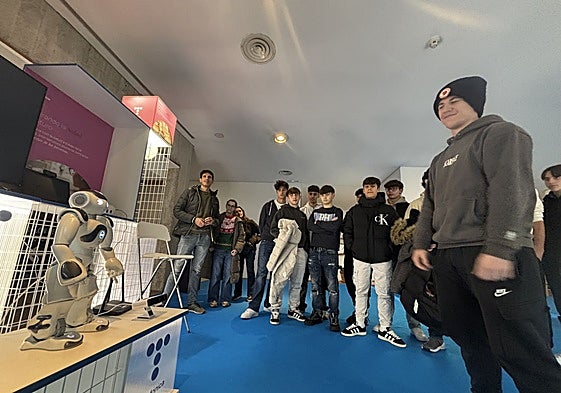 Un grupo de estudiantes ante un robot dedicado a ayudar a la rehabilitación motora de niños.