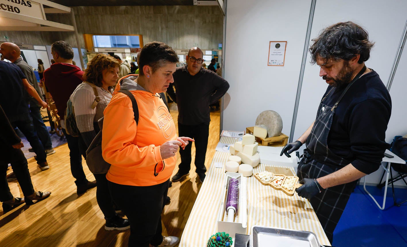Una mujer observa un buen surtido de quesos en un estand.