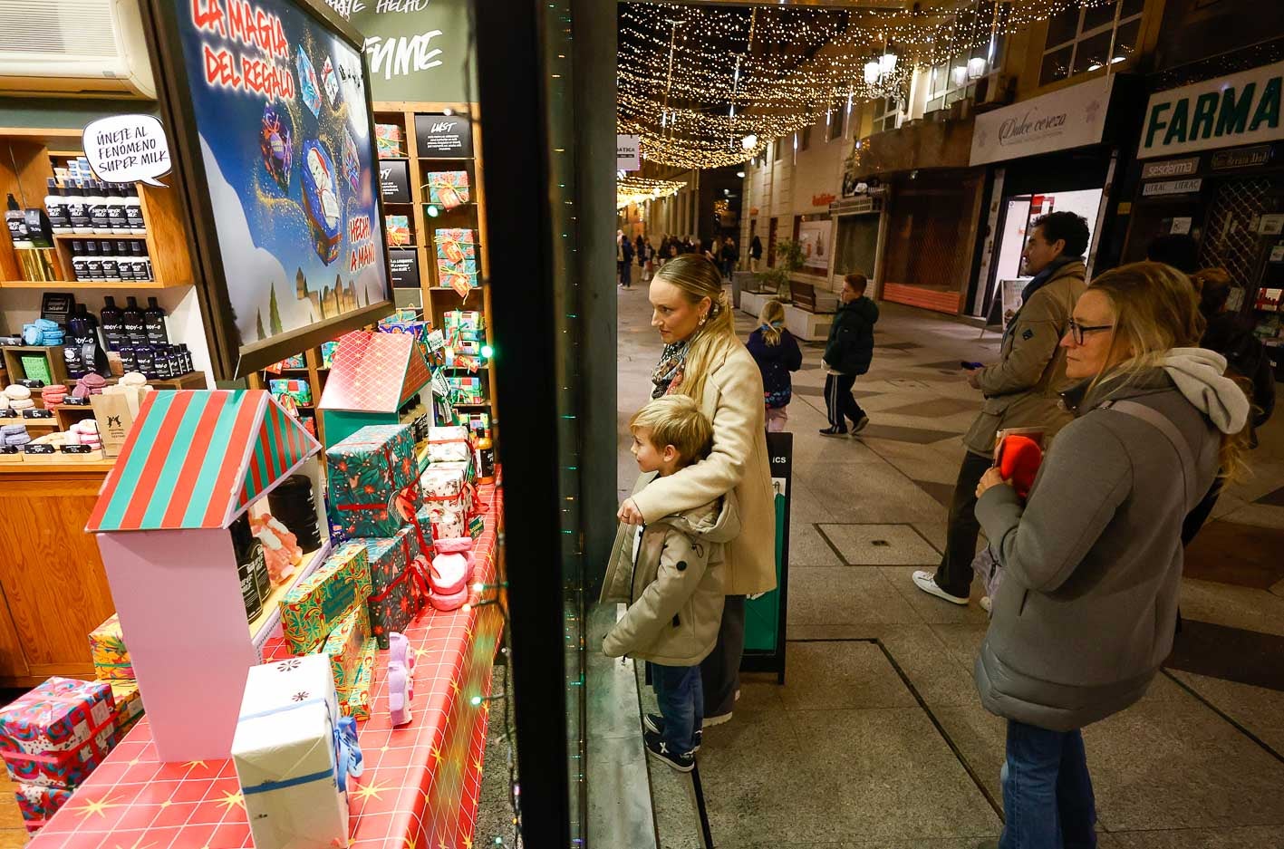 Una familia observa el escaparate navideño de una tienda de la calle San Francisco.