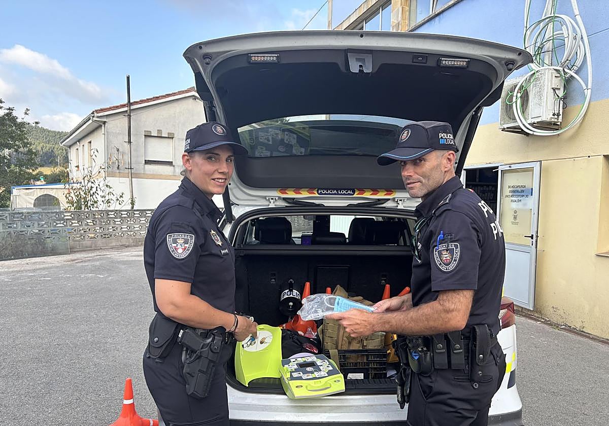 Los policías Gema y Rubén junto al Desfibrilador Externo Semiautomático que llevan en el coche.