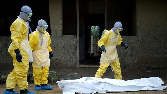 Trabajadores de la Cruz Roja de Guinea desinfectan un cadáver.