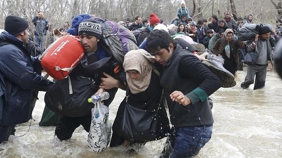Inmigrantes cruzan a pie un río en su camino. 