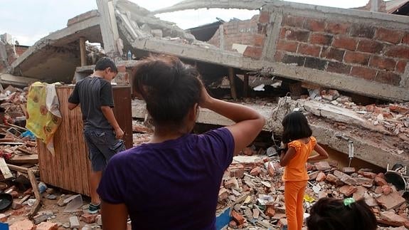 Una familia llega a una casa colapsada por el terremoto.