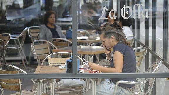 Una mujer fumando en una terraza. 