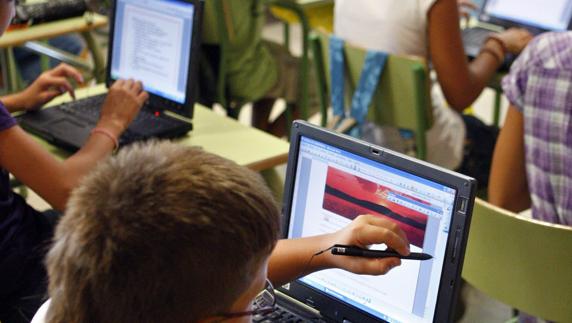 Varios niños utilizan ordenadores en un aula.