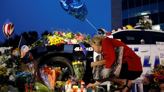 Una mujer enciende una vela en el lugar donde un policía fue asesinado.