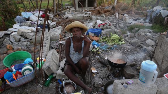 Una mujer cocina en los restos de su casa totalmente destruida tras el paso del huracán 'Matthew'. 