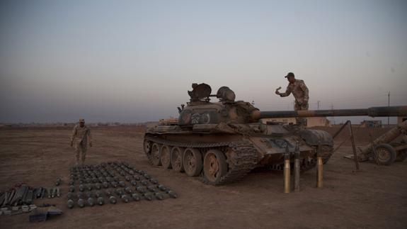 Dos soldados iraquíes preparan morteros, bombas y tanques incautados al Daesh.