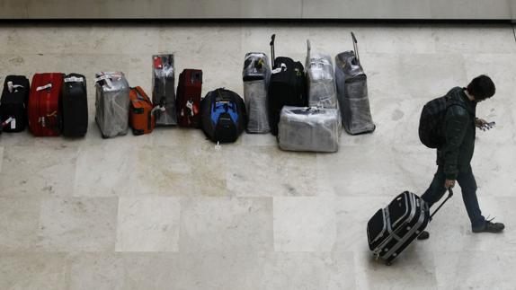 Pasajero traslada su maleta tras recogerla de la cinta transportadora del aeropuerto de Barajas.