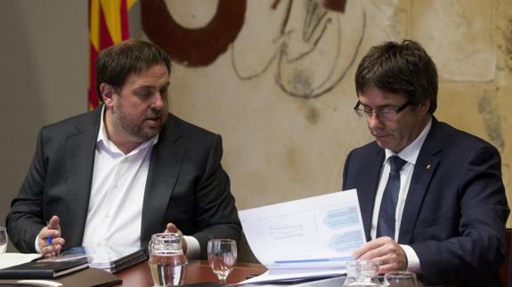 l vicepresidente catalán y conseller de Economía y Hacienda, Oriol Junqueras (i), y el presidente de la Generalitat, Carles Puigdemont (d), miran el dossier con los presupuestos del 2017.