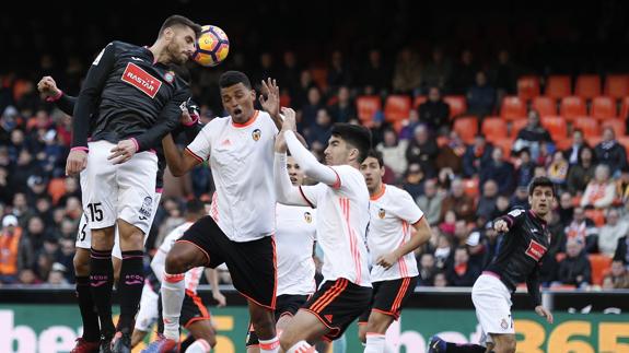 El defensa del Espanyol, David López, remata ante el defensa del Valencia, Aderlan.