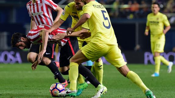 Raúl García cae ante dos futbolistas del Villarreal. 